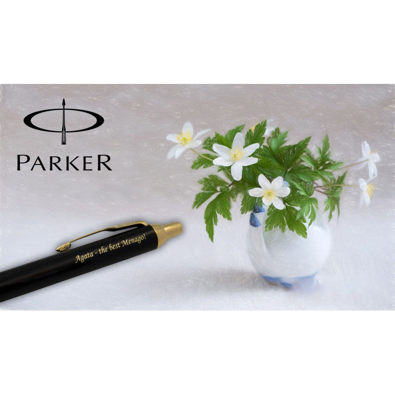 Czarny długopis Parker IM GT z grawerem „Agata – the best Menago!” na tle białych kwiatów i wazonu, z logo Parker.