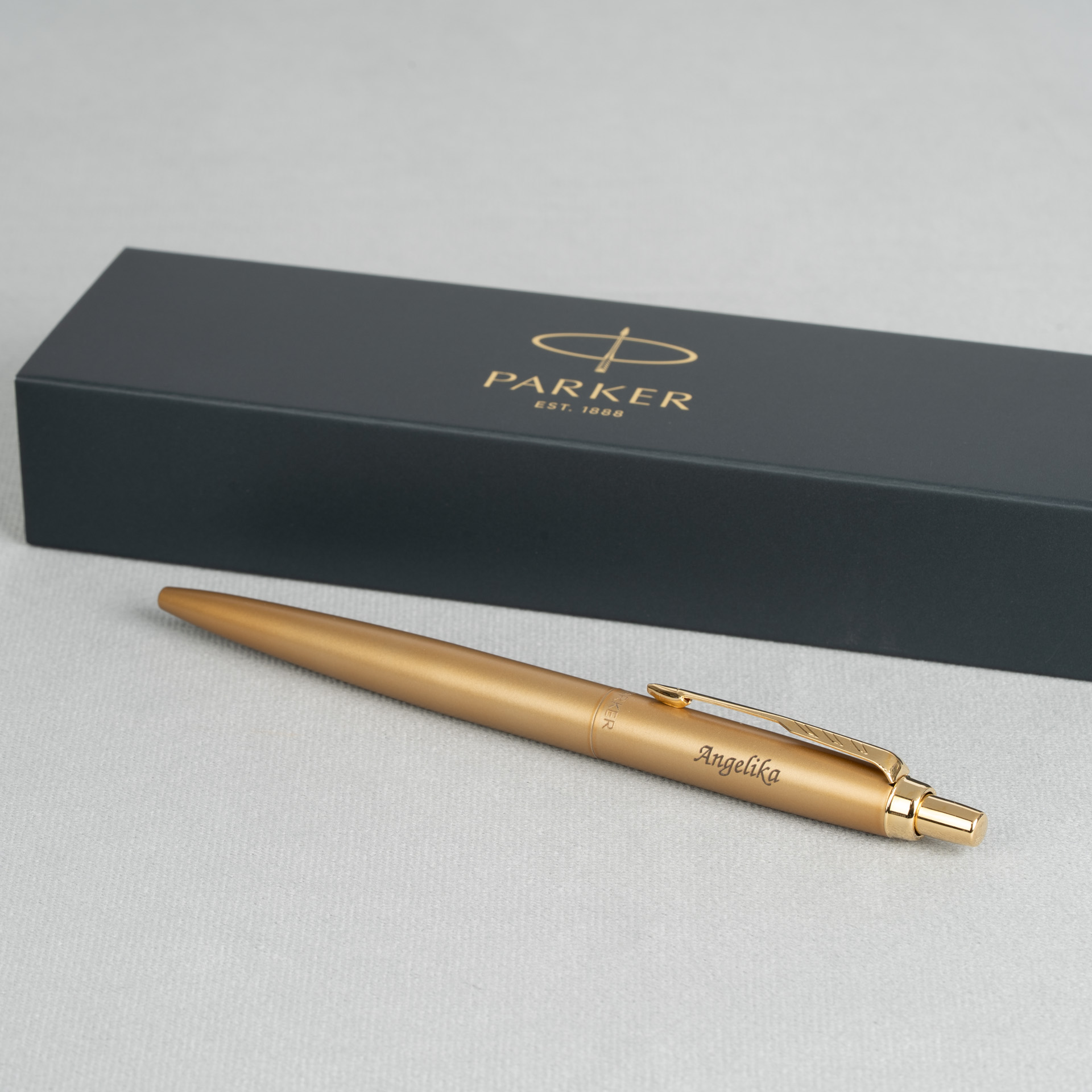 Długopis Parker Jotter XL Monochrome Gold z grawerem Angelika na tle pudełka Parker.
