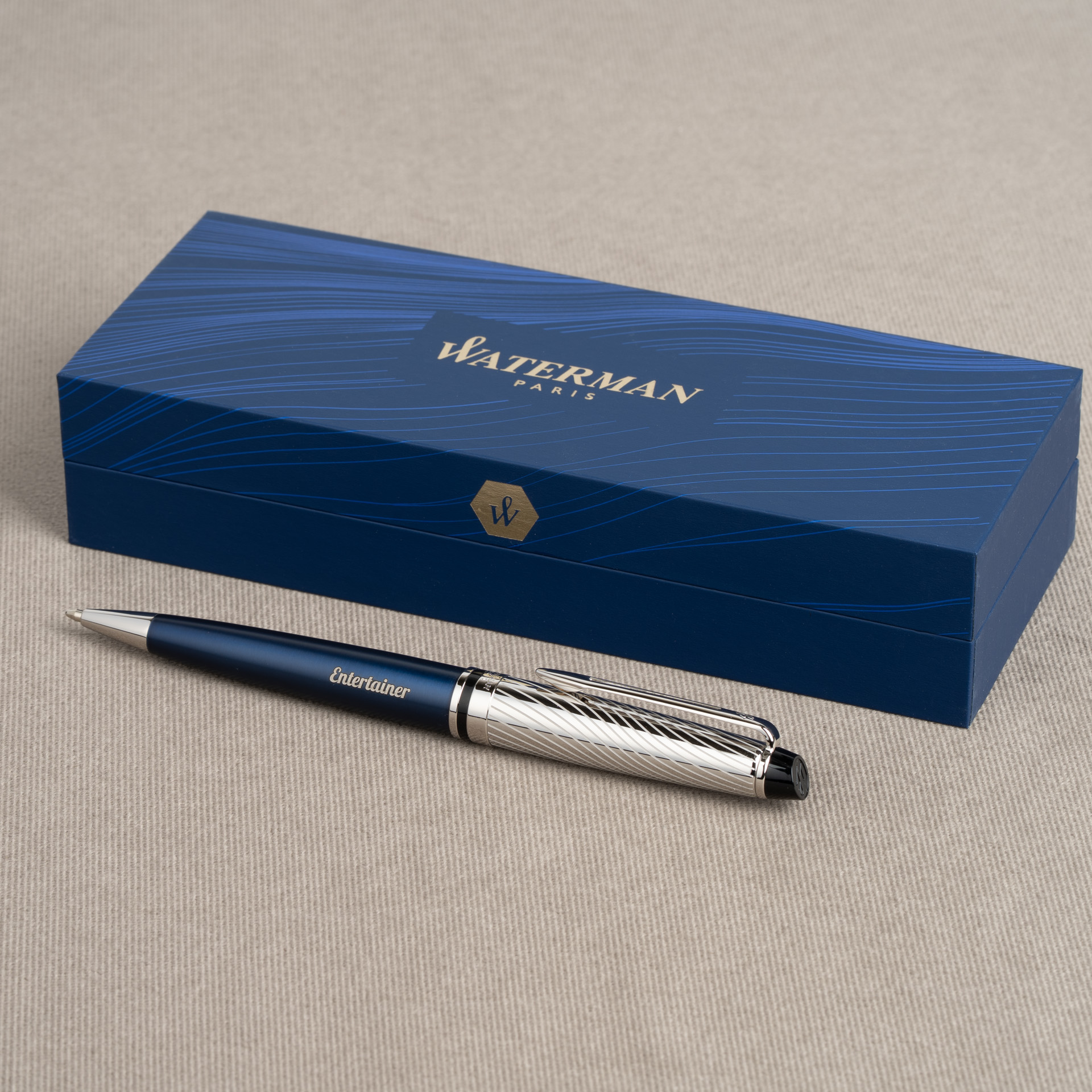 Długopis Waterman Expert Deluxe Metallic Niebieski z grawerem „Entertainer” obok eleganckiego pudełka Waterman.